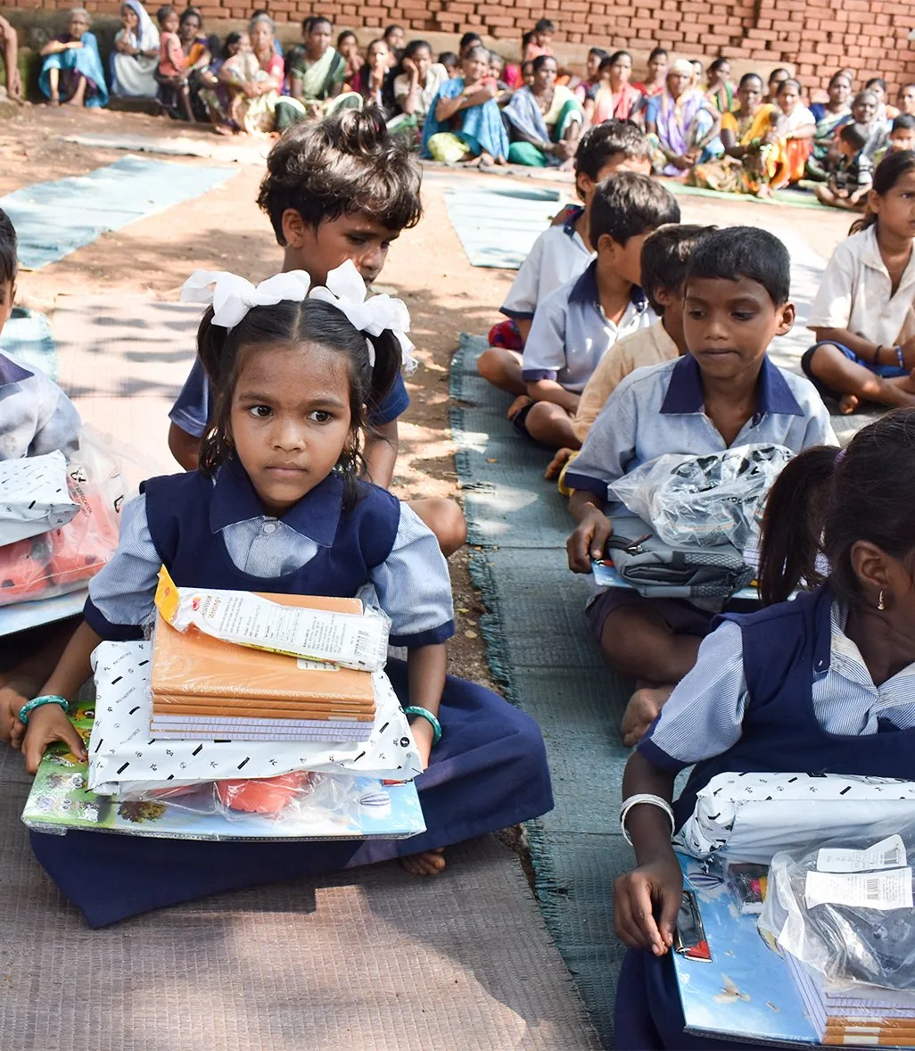 A young girl seated with school kits at a Shiksha Seva Foundation distribution drive