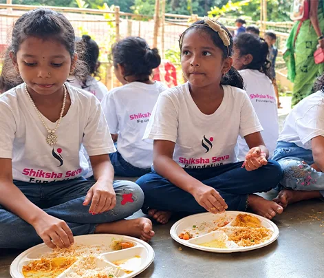 Girls sharing a meal seated along a school wall