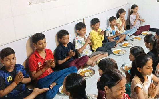 Children with folded hands before a hot meal at an Annadaan nutrition centre