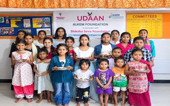 Children holding plates of food at the UDAAN centre run with Alkem Foundation